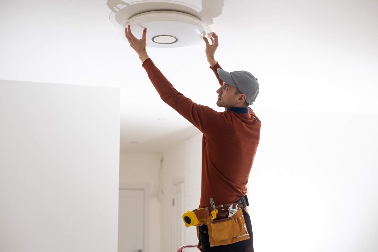 Electrician installing a modern ceiling light fixture