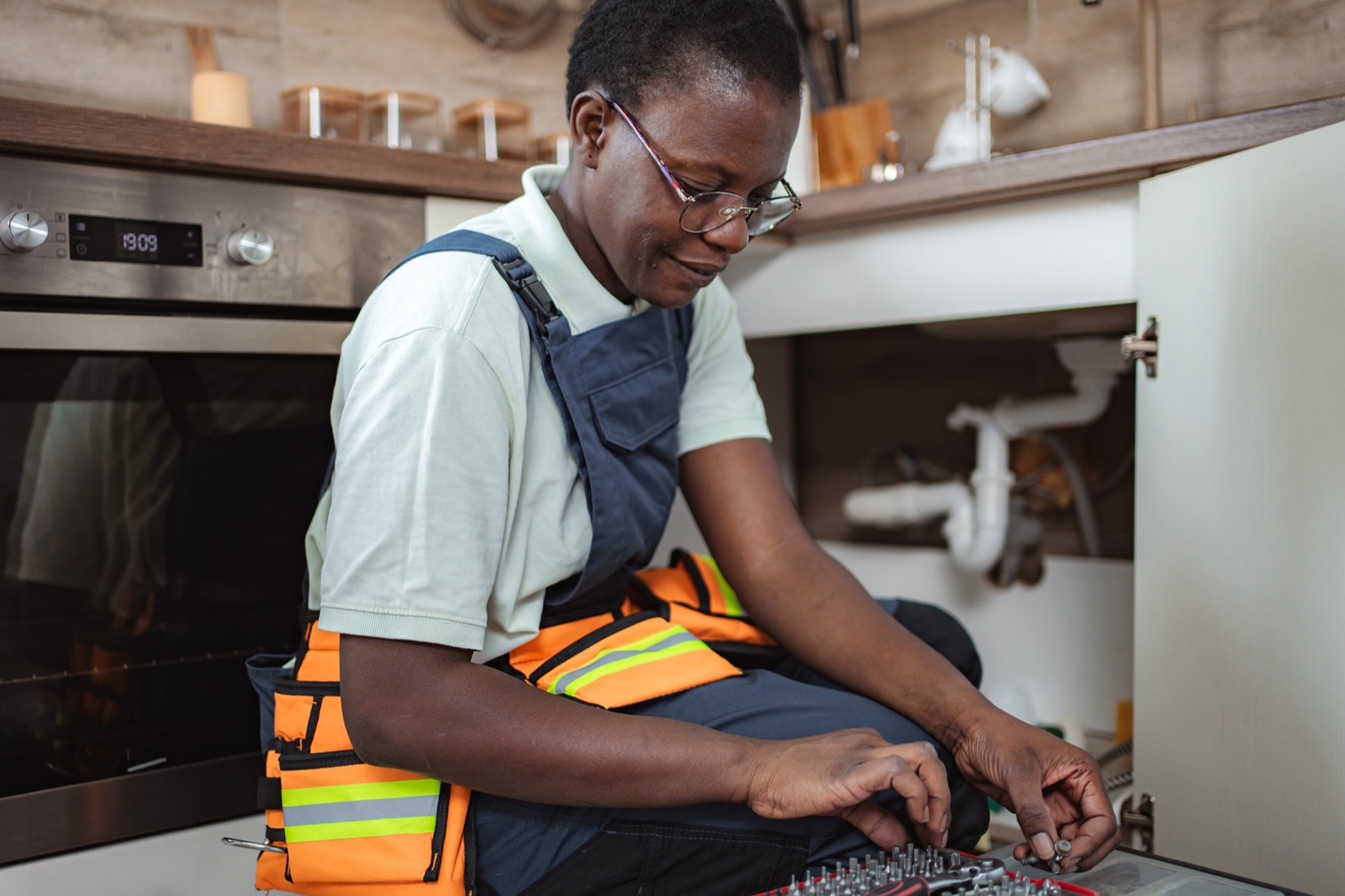 Licensed plumber carrying out a member's annual inspection under a kitchen sink