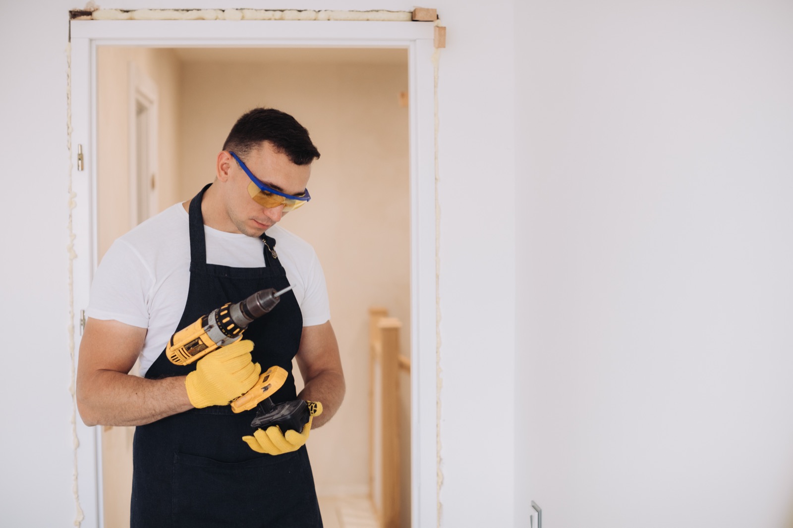 Handyman using a drill to repair a door frame