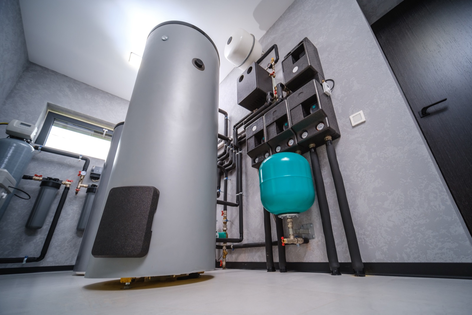 Basement utility area with water tank and drainage plumbing