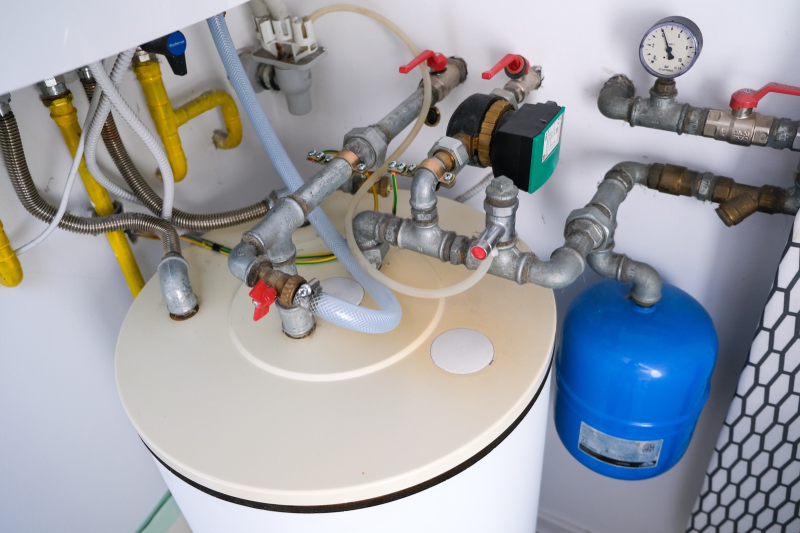 Water heater tank with pipes and a pressure gauge