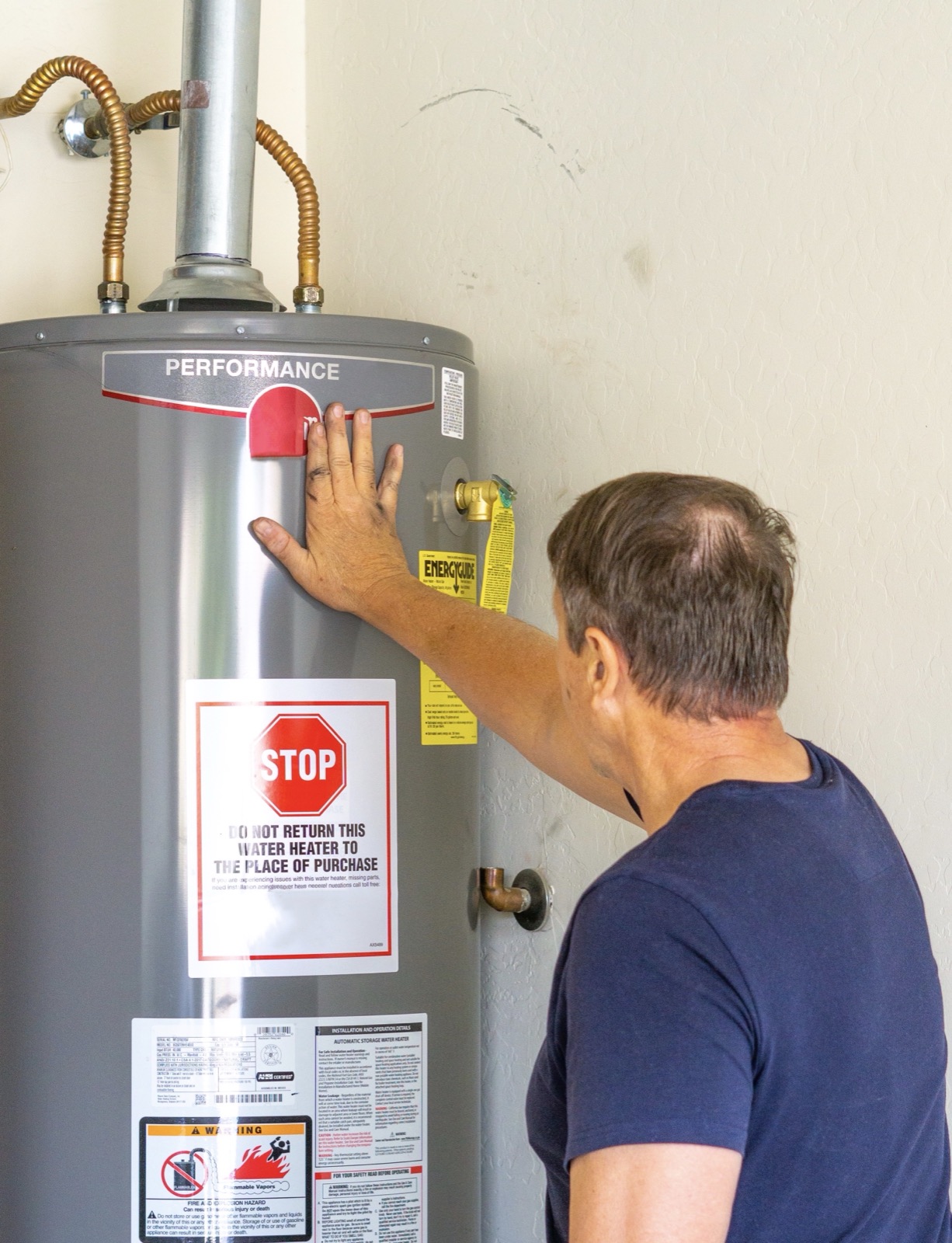 Homeowner inspecting a home water heater unit to diagnose no hot water