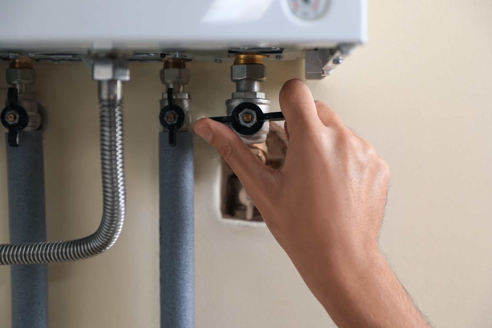 Hand adjusting a water valve on a home plumbing line