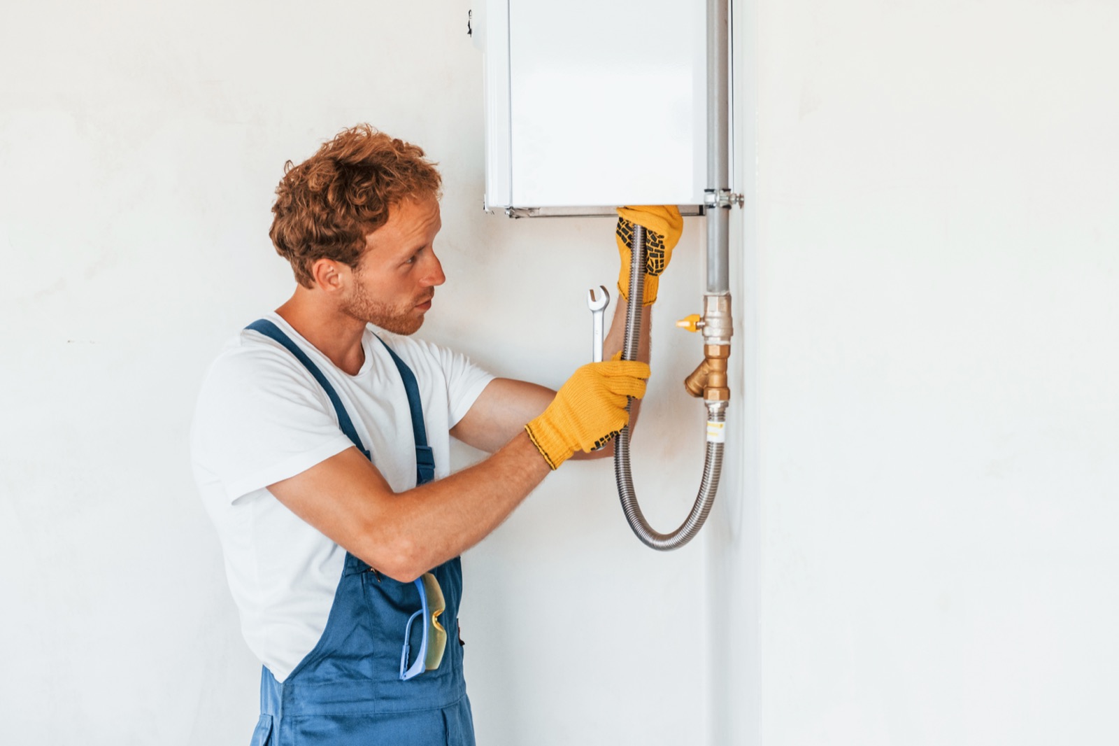 Plumber servicing a water heater's burner and pilot assembly