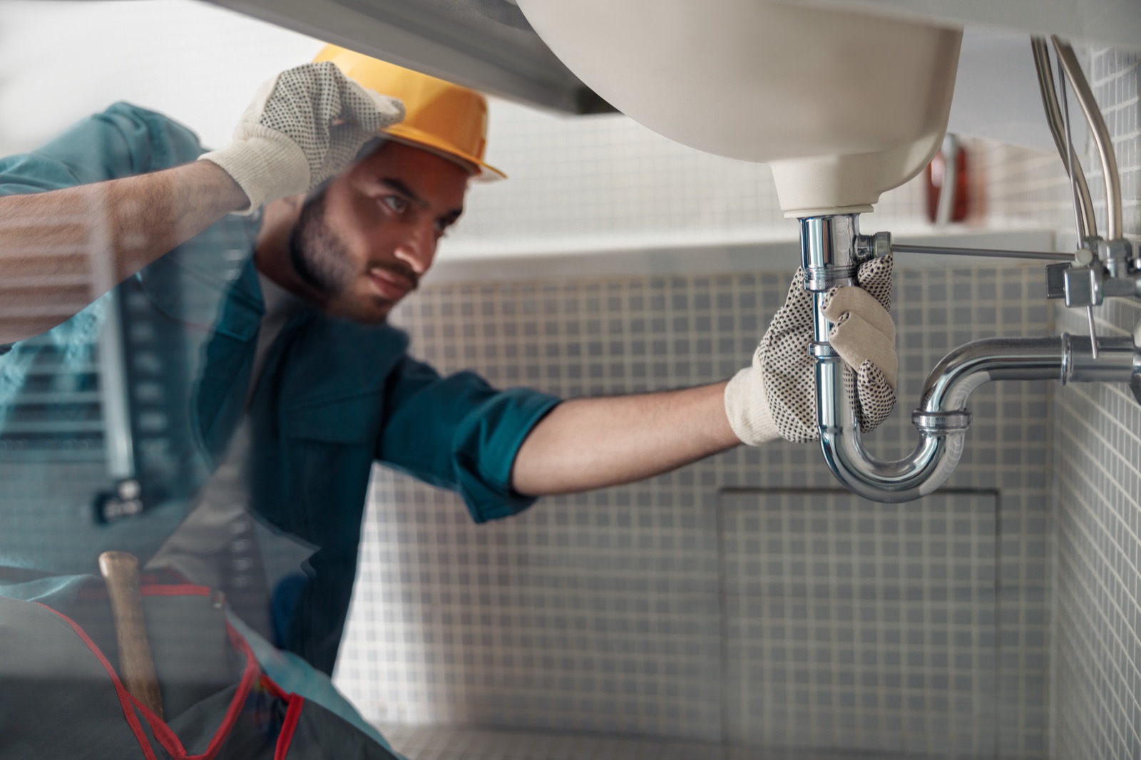 Plumber repairing a bathroom sink pipe in a Corinth home