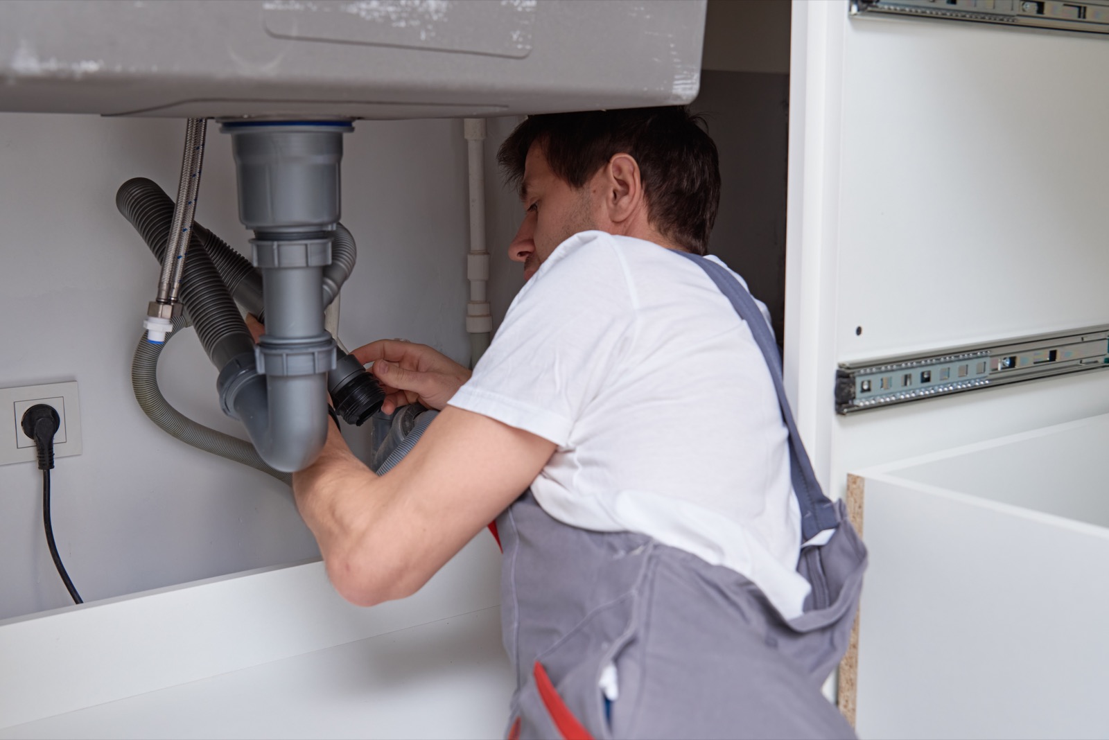 Plumber repairing a sink drain pipe in a home in The Colony