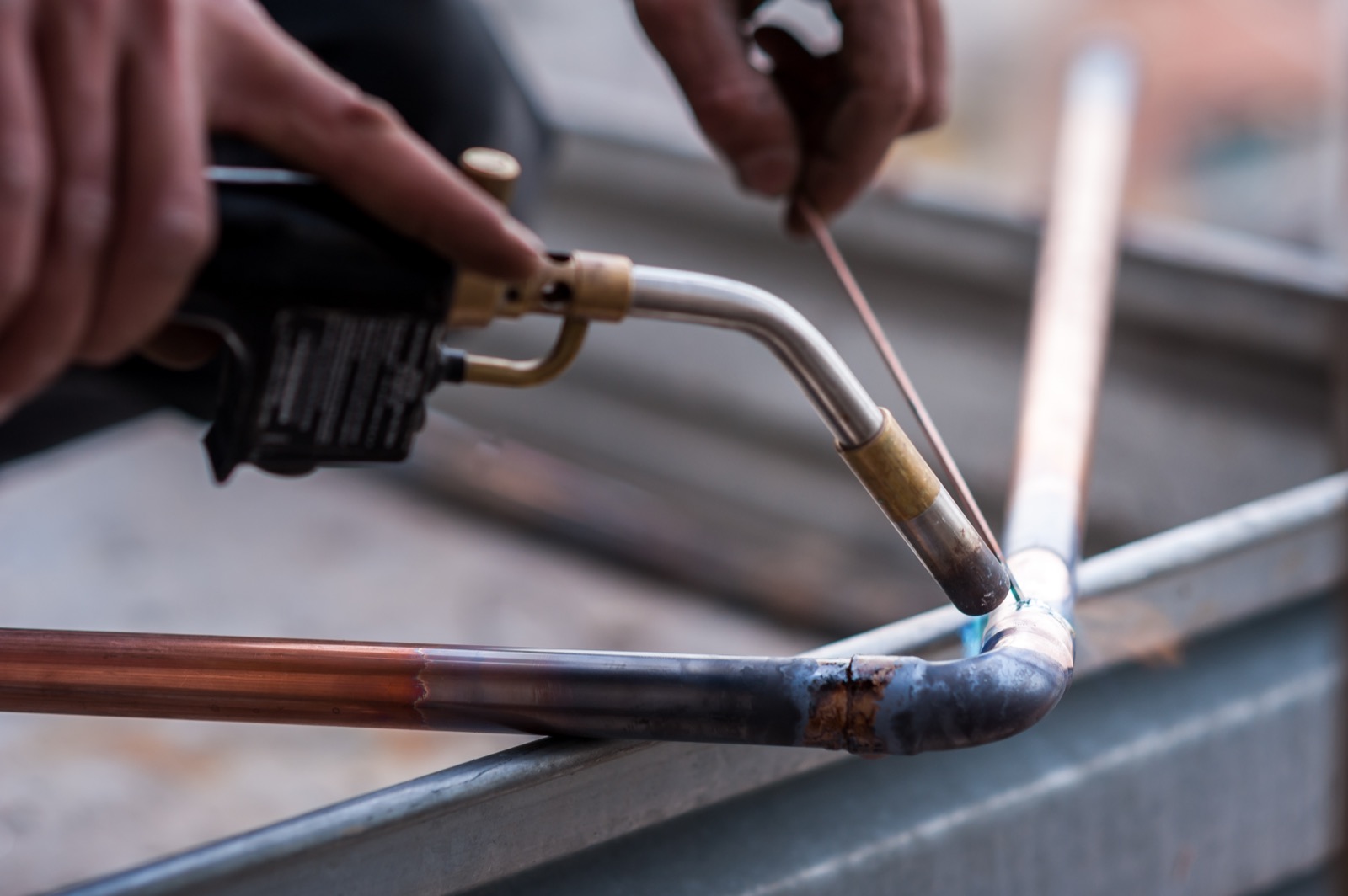 Plumber soldering copper pipe during a repipe in an older home