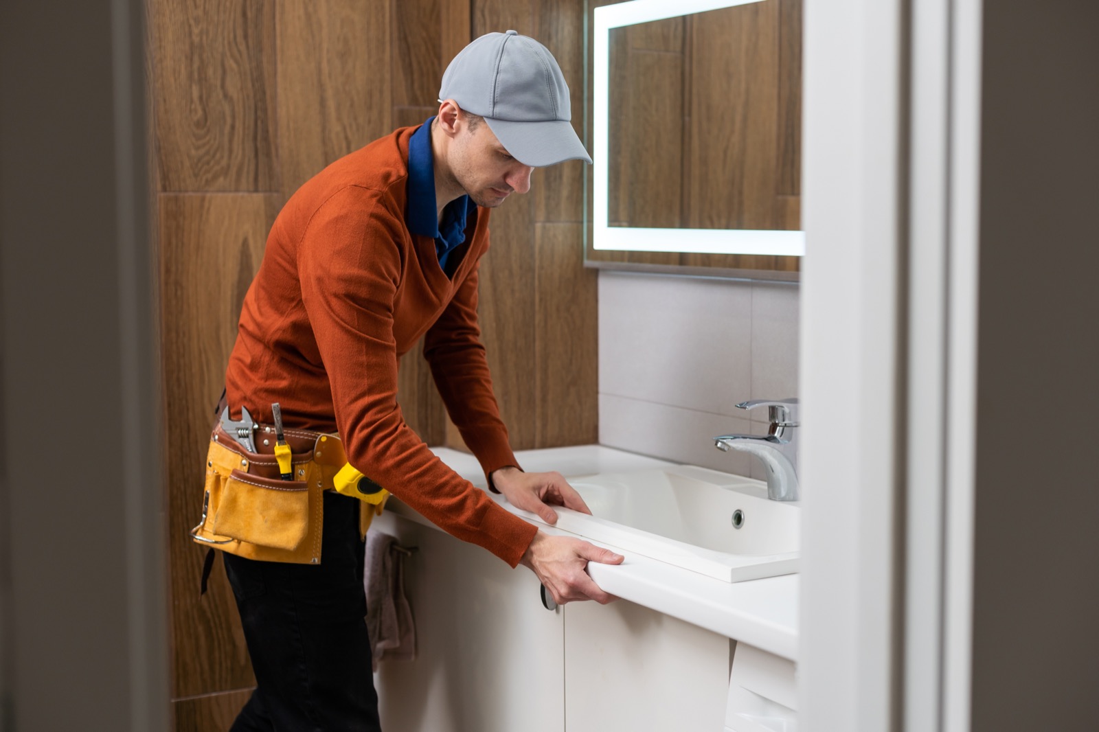 Handyman resealing a shower enclosure in a bathroom