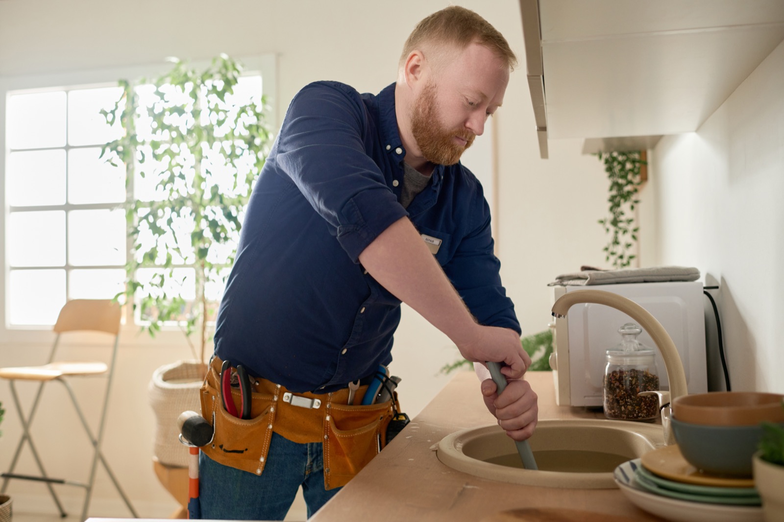 Plumber removing a stubborn blockage from a household drain