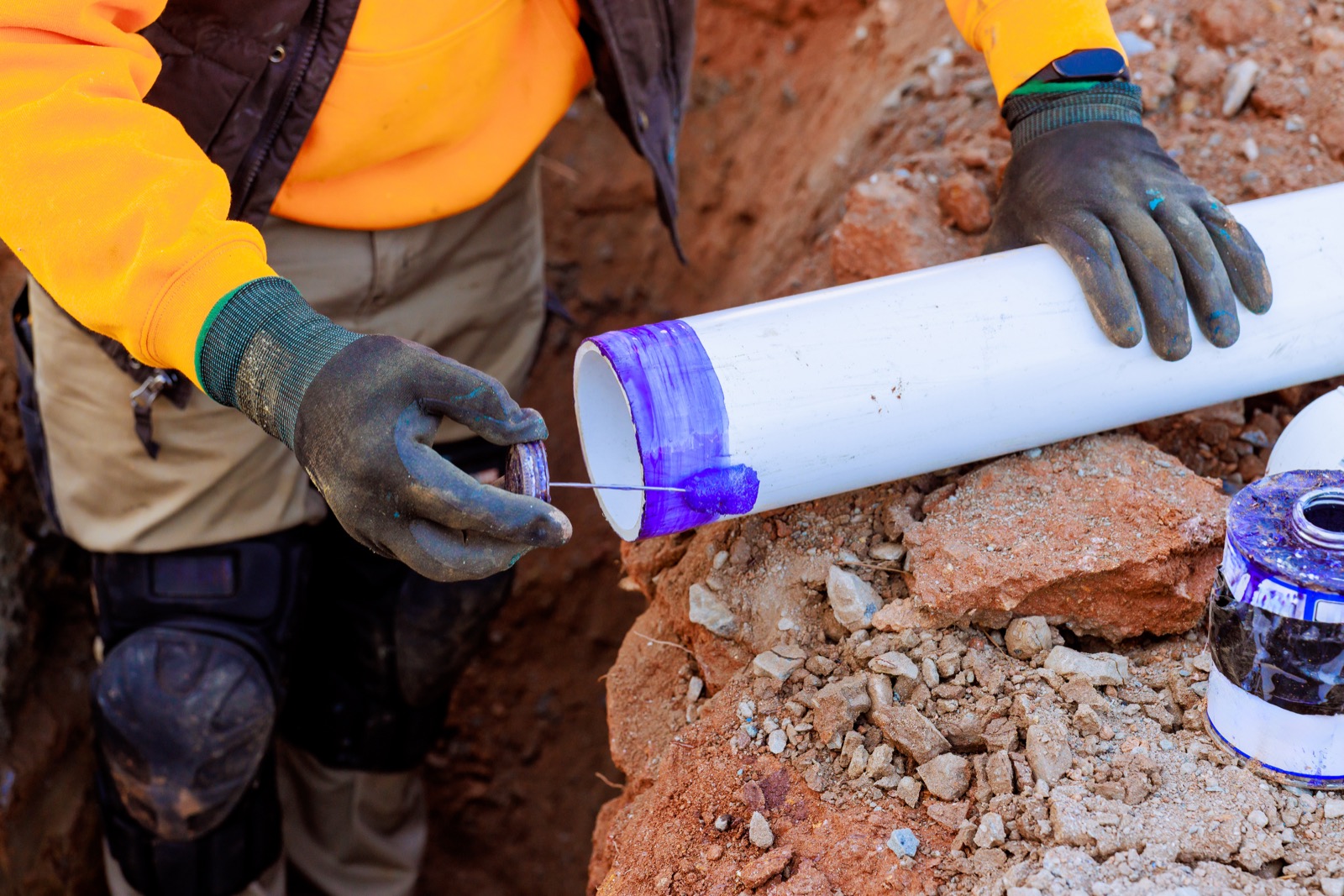 Worker preparing PVC pipe for an outdoor plumbing installation